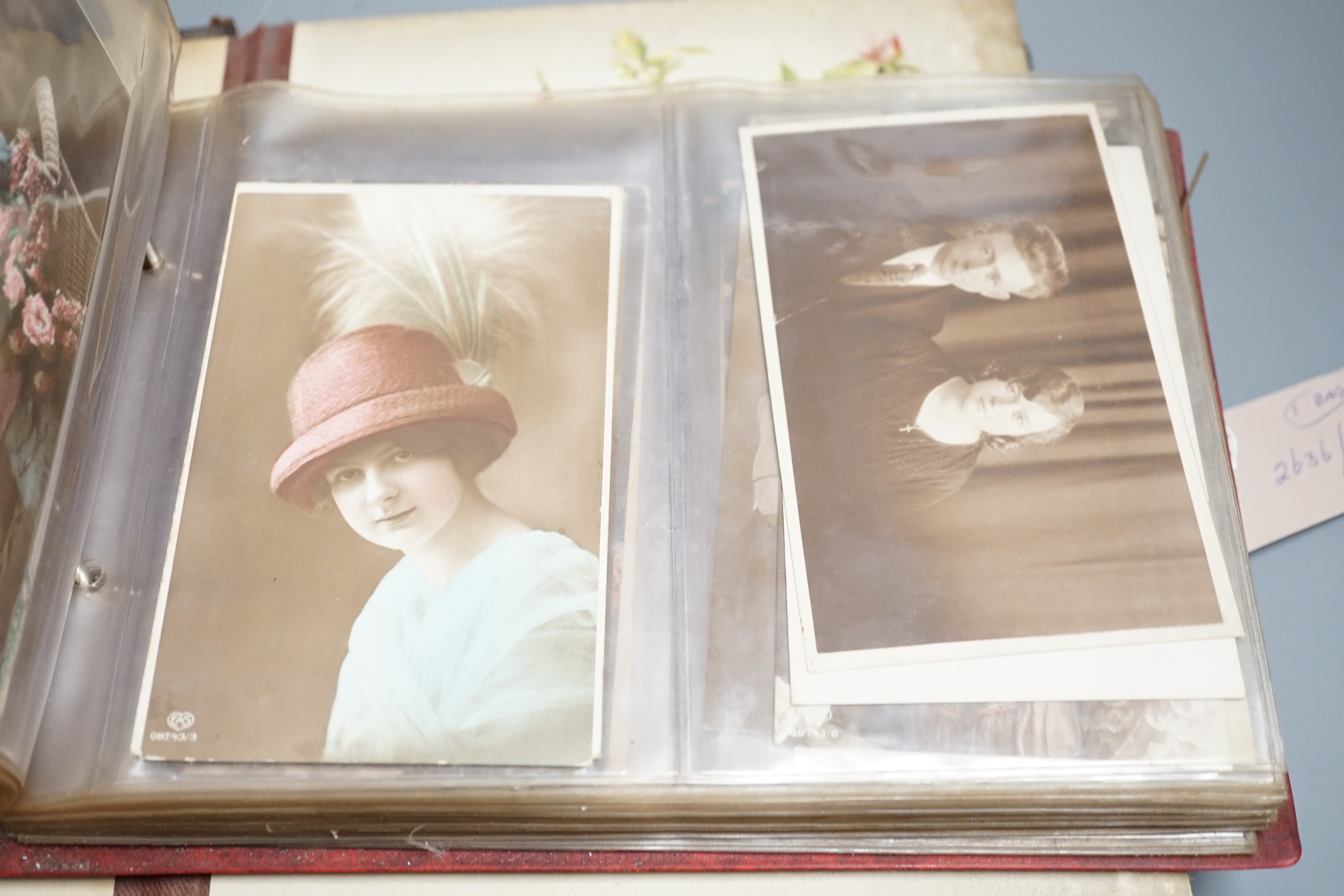 An early 20th century postcard collection in two albums and an empty late Victorian leather photo album